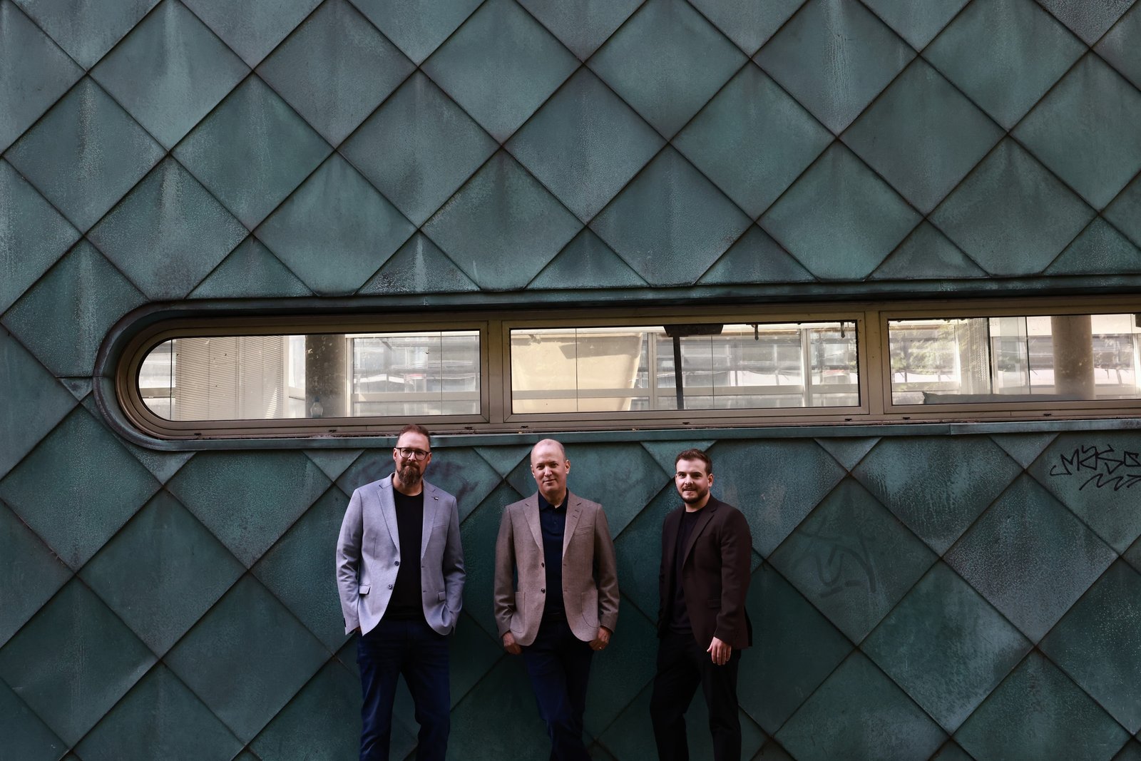 Christian Tramborg, Matthias Johansson und Sebastian Pille vor einer markanten Metallfassade